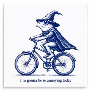 May include: A whimsical illustration of a frog riding a bicycle, dressed in a wizard's hat and cape. The image is in shades of blue and white, with the text "I'm gonna be so annoying today" at the bottom.