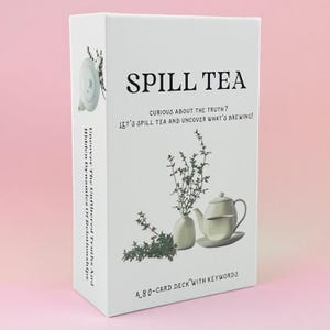 May include: A white rectangular card deck box titled Spill Tea. The front features a teapot, a teacup, and a sprig of herbs, with the text: Curious about the truth? Let's spill tea and uncover what's brewing! A 80-card deck with keywords.