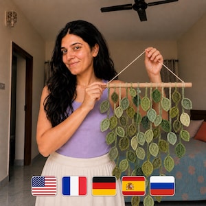 May include: A decorative wall hanging made from crocheted green leaves, suspended from a wooden dowel. The leaves are in various shades of green, offering a textured, natural look. Ideal for interior decoration, it brings a touch of nature to a room.