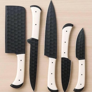 May include: A set of five kitchen knives featuring black blades with a textured, hammered finish and white handles secured with three rivets. The collection includes a rectangular cleaver, a long slicing knife, a chef knife, and two paring knives.