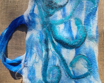 Könnte beinhalten: Eine gefilzte Tasche mit einem blau-weißen Batikmuster und einem dunkelblauen Oktopus-Design auf der Vorderseite. Die Tasche hat einen integrierten Griff und eine weiche, strukturierte Oberfläche mit sichtbaren Wollfasern im Material.