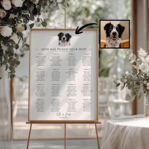 May include: A white wedding seating chart sign on a gold easel featuring the text "SETH HAS PICKED YOUR SPOT" and a black and white portrait of a dog. A small inset box shows the original color photograph of the same dog with a black arrow pointing to it.
