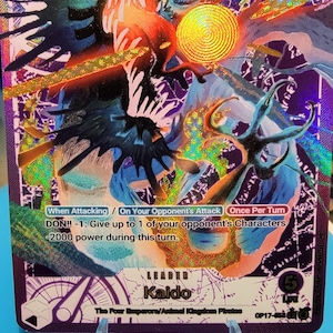 May include: A purple One Piece trading card featuring the character Kaido in a dynamic pose with blue and orange energy effects. The card displays the text Leader Kaido, The Four Emperors/Animal Kingdom Pirates, 5000 power, and 5 life points.