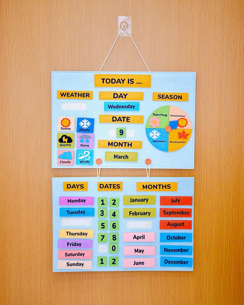 K&ouml;nnte beinhalten: Ein Filz-Lernkalender mit Abschnitten f&uuml;r Wetter, Tag, Datum, Monat und Jahreszeit. Enth&auml;lt farbenfrohe Etiketten f&uuml;r Wochentage, Daten und Monate. Der Kalender h&auml;ngt an einer Holzt&uuml;r.