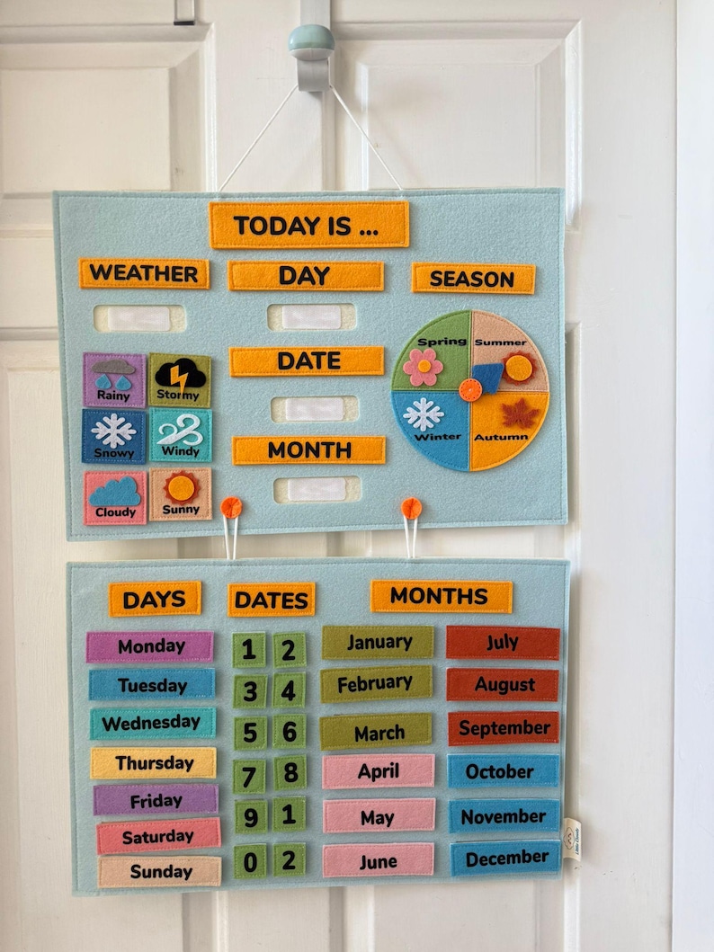 K&ouml;nnte beinhalten: Hellblauer Filz-Lernkalender mit orangefarbenen Textetiketten f&uuml;r Wetter, Tag, Datum, Monat und Jahreszeit. Enth&auml;lt Wettersymbole und ein saisonales Rad. Der untere Bereich zeigt Tage, Daten und Monate mit farbigen Etiketten.