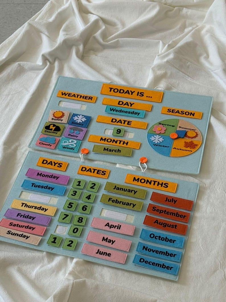 K&ouml;nnte beinhalten: Ein p&auml;dagogischer Filz-Kalender mit Abschnitten f&uuml;r Wetter, Tag, Datum, Monat und Jahreszeit. Enth&auml;lt Etiketten f&uuml;r Wochentage, Zahlen und Monate. Der Text "TODAY IS..." ist oben sichtbar. Der Kalender befindet sich auf einer wei&szlig;en Oberfl&auml;che.