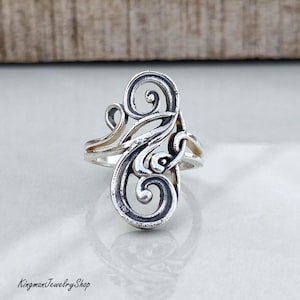 May include: A sterling silver ring featuring an elongated, openwork design composed of intricate, swirling scroll patterns. The metal has a polished finish with darkened, recessed areas that highlight the curves and loops of the metalwork.