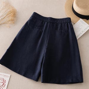 Puede incluir: Unos pantalones cortos de color azul marino oscuro con cintura el&aacute;stica, dos bolsillos traseros ribeteados y una silueta de pierna ancha. Los pantalones cortos est&aacute;n confeccionados en un tejido texturizado y se muestran planos.