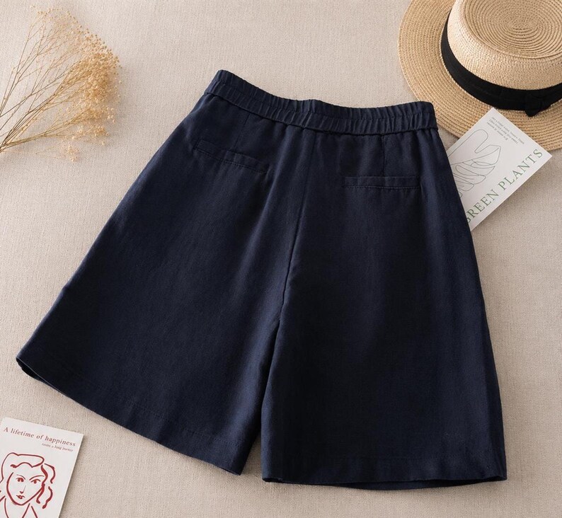 Puede incluir: Unos pantalones cortos de color azul marino oscuro con cintura el&aacute;stica, dos bolsillos traseros ribeteados y una silueta de pierna ancha. Los pantalones cortos est&aacute;n confeccionados en un tejido texturizado y se muestran planos.