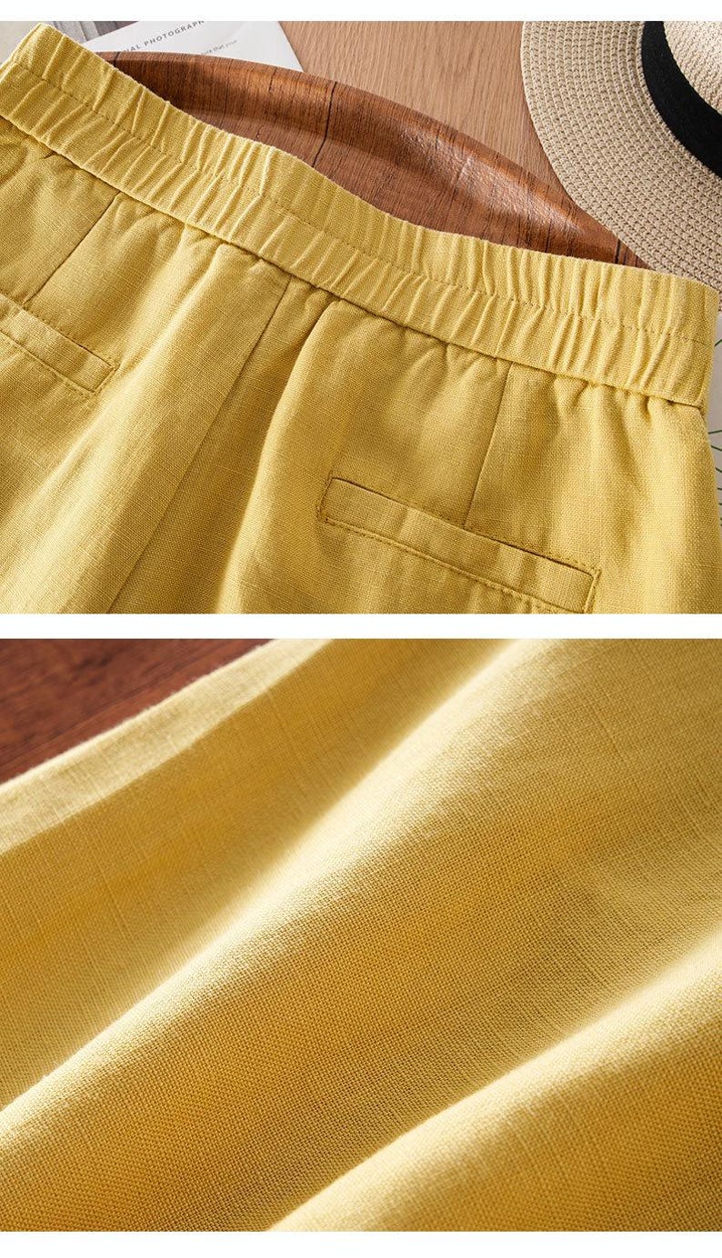 Puede incluir: Pantalones cortos de color amarillo mostaza con cintura el&aacute;stica, detalles fruncidos y dos bolsillos falsos de ojal en la parte delantera. La tela tiene una textura tejida visible y la prenda se muestra en dos vistas para resaltar la cintura y el tejido.