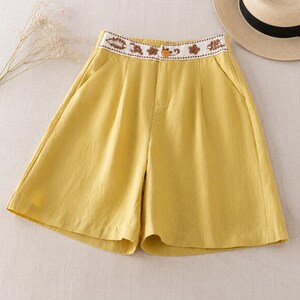 Puede incluir: Pantalones cortos de color amarillo mostaza con dise&ntilde;o de cintura alta, una banda blanca decorada con bordados florales marrones y un cierre de un solo bot&oacute;n amarillo. Tienen frente plisado, bolsillos laterales y pernera ancha.