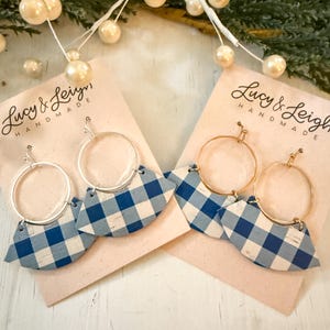 May include: Two pairs of earrings with a blue and white gingham pattern. Each earring has a silver or gold hoop and a fan-shaped cork design. The earrings are displayed on pink cards with the text "Lucy & Leigh Handmade".