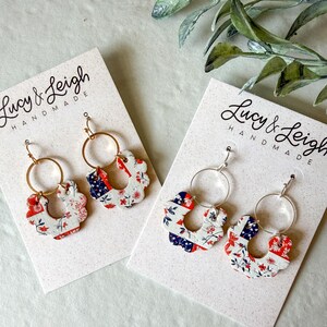 Puede incluir: Dos pares de pendientes en tarjetas de presentación blancas con la etiqueta Lucy & Leigh Handmade. Cada pendiente presenta un aro dorado o plateado unido a un dije festoneado en forma de herradura con un patrón floral y geométrico rojo, blanco y azul.