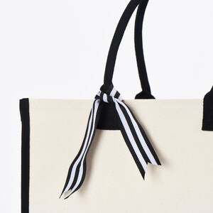 a white bag with a black and white striped bow