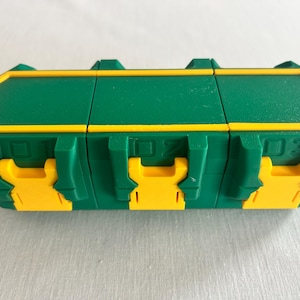 Peut inclure: Un conteneur de rangement rectangulaire vert doté de trois compartiments distincts, chacun sécurisé par un loquet jaune. L'avant du conteneur affiche les chiffres 01, 02 et 03 en relief au-dessus de chaque mécanisme de verrouillage jaune.
