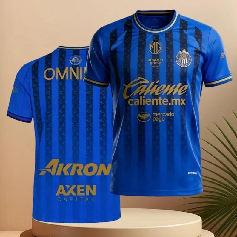 May include: Blue soccer jersey with black vertical stripes and gold accents. The jersey features the text "Caliente caliente.mx" and "AKRON AXEN CAPITAL". The team logo is on the chest.