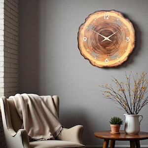 May include: A round wall clock crafted from a natural wood slice with visible tree rings, featuring a dark brown centre, a lighter outer edge, white numerals at 12, 3, 6, and 9, and thin gold-coloured metal clock hands centred on the face.
