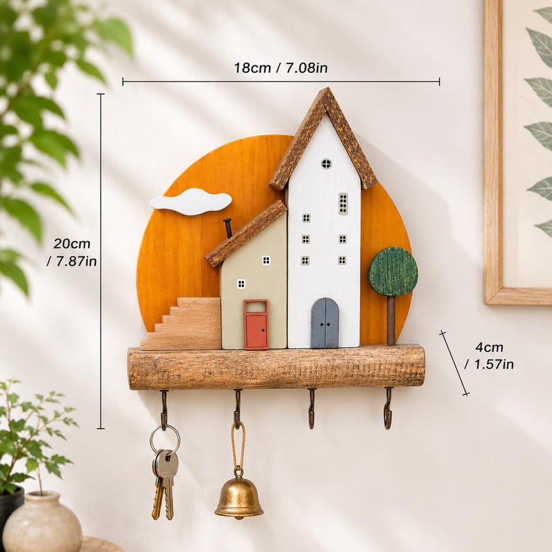 Puede incluir: Un soporte de pared de madera para llaves con dise&ntilde;o de casas sobre un fondo circular amarillo. Incluye cuatro ganchos met&aacute;licos, con llaves y una campana colgadas de dos de ellos. Las dimensiones son 18 cm de ancho, 20 cm de alto y 4 cm de profundidad.