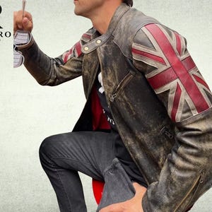Puede incluir: Una chaqueta de cuero marrón desgastado con un diseño de bandera Union Jack en las mangas, cuello mao con cierre de botón a presión y bolsillos con cremallera. La chaqueta tiene un acabado envejecido e incluye el logo RIVARO JACKETS.