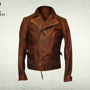 May include: A brown leather motorcycle jacket featuring an asymmetrical front zipper closure, a wide notched collar, a slanted zippered chest pocket, and a small flap pocket on the lower right side. The jacket includes long sleeves with cuffs.