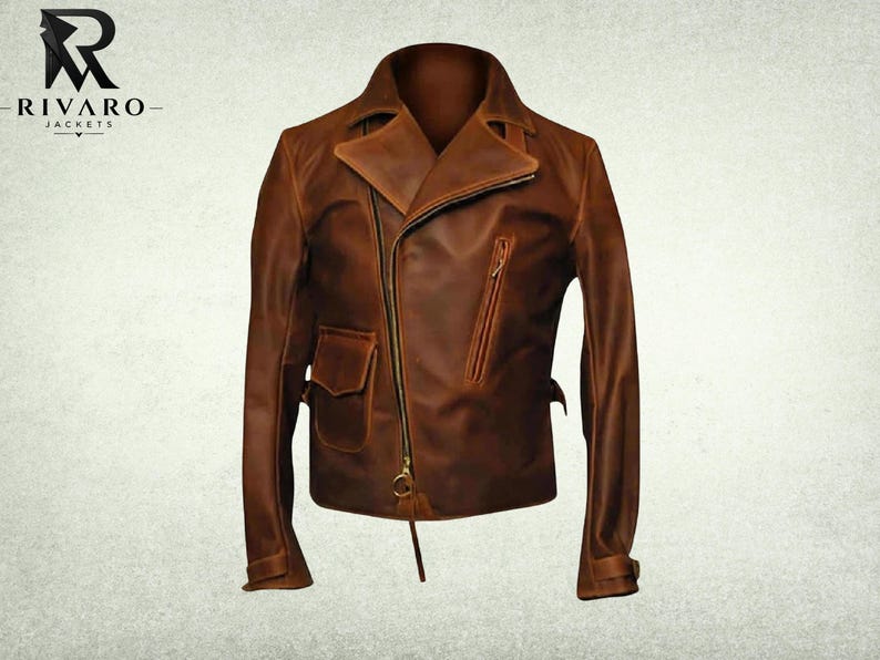 May include: A brown leather motorcycle jacket featuring an asymmetrical front zipper closure, a wide notched collar, a slanted zippered chest pocket, and a small flap pocket on the lower right side. The jacket includes long sleeves with cuffs.