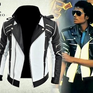 May include: A black and white jacket featuring multiple silver-toned zippers on the sleeves and chest, a wide lapel, and a front zipper closure. The design includes vertical color-blocked panels and metallic stud accents along the front seams.