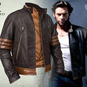 Può includere: Una giacca in pelle marrone scuro con colletto rialzato, chiusura frontale con zip e tre strisce orizzontali color marrone chiaro su ogni manica. La giacca presenta una fodera interna color marrone chiaro e una fascia in pelle lungo l'orlo inferiore. Il logo Rivaro Jackets è visibile.