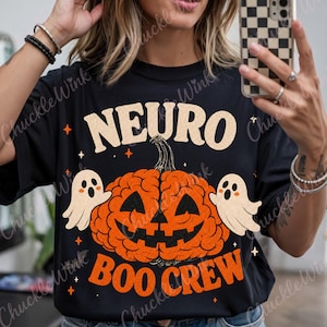以下が含まれることがあります： 黒いTシャツで、人間の脳の形をしたオレンジ色のカボチャにジャック・オー・ランタンの顔が描かれたグラフィックが特徴です。カボチャの両脇には小さな白い幽霊が2体います。上部にベージュで「NEURO」、下部にオレンジで「BOO CREW」という文字がプリントされています。