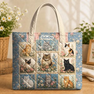 May include: A quilted tote bag featuring a grid of nine panels, each displaying a different cat breed surrounded by flowers. The name Valentina is printed at the top centre. The bag has a light blue floral background and two cream-coloured handles.