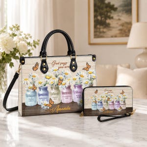 Può includere: Una borsa strutturata e un portafoglio abbinato con sfondo effetto legno chiaro, bouquet di margherite bianche in barattoli di vetro colorati e farfalle arancioni. Il testo recita God says you are Unique, SPECIAL, Lovely, PRECIOUS, Strong e Amanda.