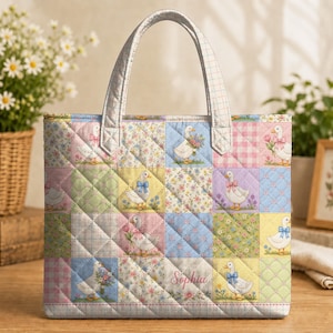 May include: A quilted tote bag featuring a patchwork design of white geese, floral patterns, and gingham checks in pastel colours. The bag has two top handles and the name Sophia is printed in cursive script on one of the lower central squares.