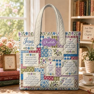 May include: A quilted tote bag featuring a patchwork design of blue, green, and purple floral and gingham patterns. The bag displays multiple rectangular panels with printed religious text and the name Charlotte in a purple decorative frame.