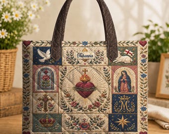 Pode incluir: Uma bolsa tote acolchoada com um emblema central do Sagrado Coração rodeado por imagens religiosas, incluindo uma pomba, um cordeiro com bandeira, uma rosa, uma cruz, uma coroa e a Virgem Maria. A bolsa tem alças castanhas e o nome Tohanna.