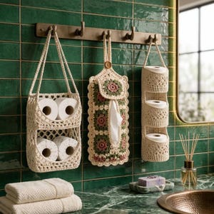 Puede incluir: Tres organizadores de baño de ganchillo color crema cuelgan de un perchero de pared de bronce. Incluye una cesta de dos niveles para papel higiénico, un dispensador de pañuelos con motivos florales y un soporte vertical de tres niveles.