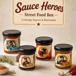 Könnte beinhalten: Vier Saucengläser mit schwarzen Deckeln, jedes mit einem individuellen Charakter-Etikett: Gyronidas, Smoky Sam, Sassy Su und Magie Mohinder. Darüber ein rechteckiges Schild mit der Aufschrift Sauce Heroes Street Food Box 4 würzige Saucen & Marinaden.
