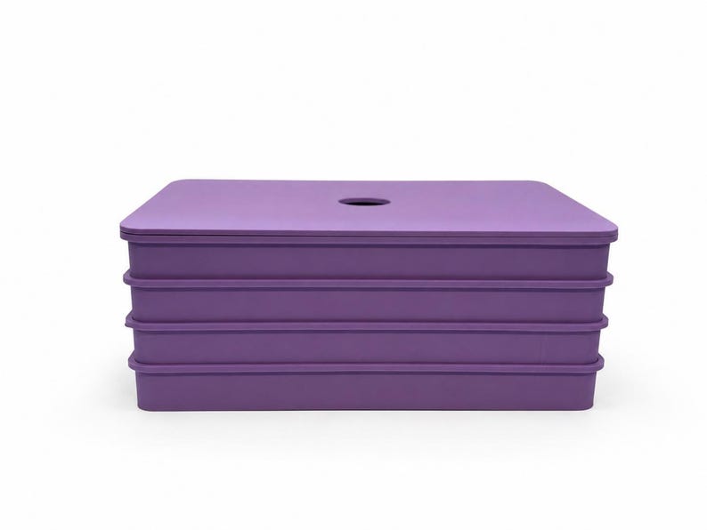 May include: A stackable, rectangular storage container in a vibrant purple hue. The container has a flat top with a circular opening and three lower sections. The design is simple and modern, suitable for various storage needs.