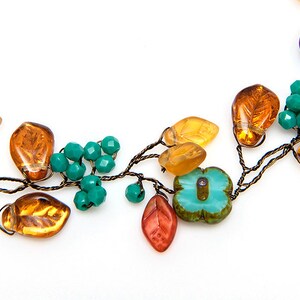 May include: A delicate necklace made with wire, amber glass leaves, turquoise blue glass beads, and a turquoise blue flower charm.