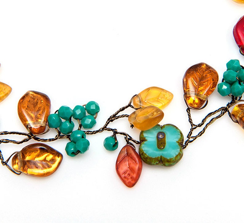 May include: A delicate necklace made with wire, amber glass leaves, turquoise blue glass beads, and a turquoise blue flower charm.