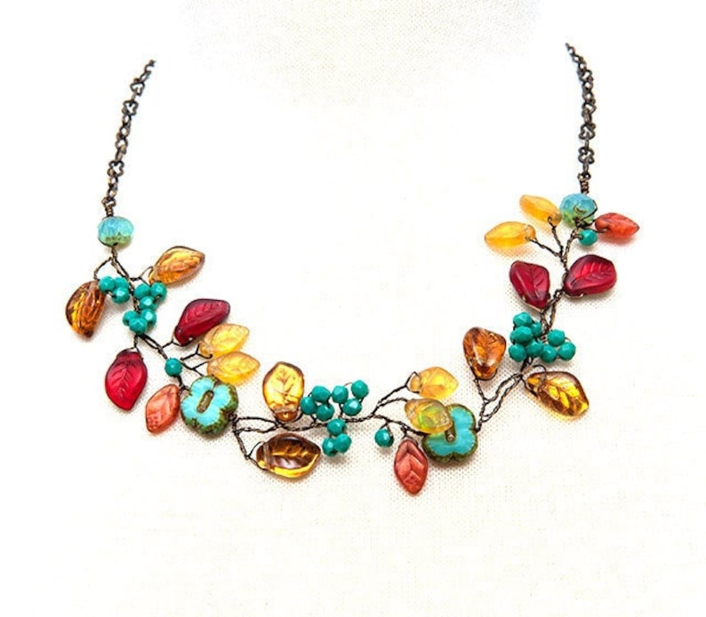 May include: A copper wire necklace with colorful glass leaves and beads. The leaves are in shades of red, orange, yellow, and green. The beads are turquoise.