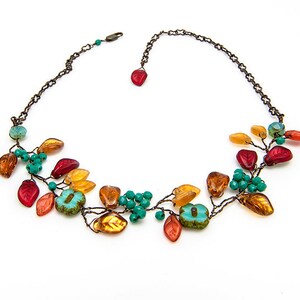 May include: A delicate necklace with a leafy design featuring orange, red, and turquoise glass beads. The necklace is made with wire and has a simple chain closure.