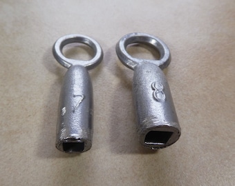May include: Two silver metal key-shaped objects with square holes at the bottom. The object on the left has the number "7" engraved on it. The object on the right has the number "8" engraved on it.