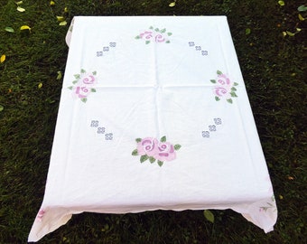 May include: White tablecloth with embroidered pink roses and green leaves. The tablecloth has a simple design with four roses evenly spaced around the center.