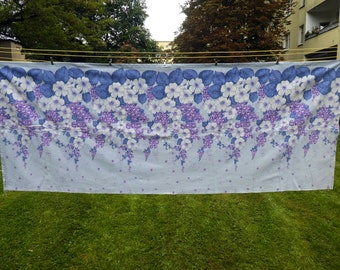May include: A blue and white floral fabric with a repeating pattern of flowers and vines. The fabric is hanging on a clothesline.