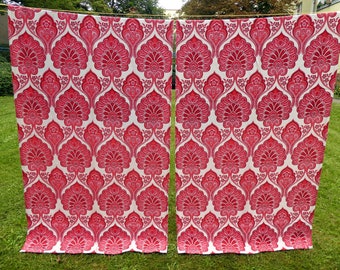 May include: Two red and white patterned curtains hanging on a clothesline in a backyard.
