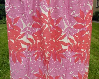 May include: A white curtain with a pink and red floral pattern. The pattern features large leaves and flowers.
