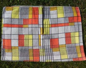 May include: A gray, yellow, orange, and white checkered throw pillow with a geometric pattern.