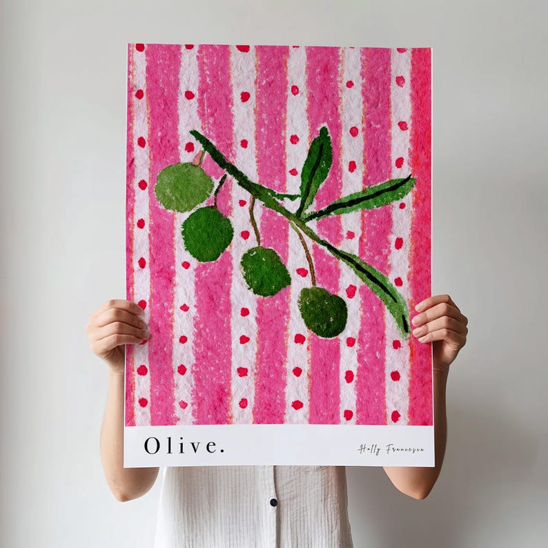 Puede incluir: Una pintura de acuarela de una rama de olivo con aceitunas verdes sobre un fondo a rayas rosa y blanco con lunares blancos. La pintura est&aacute; titulada "Olive." y firmada "Holly Franzen".