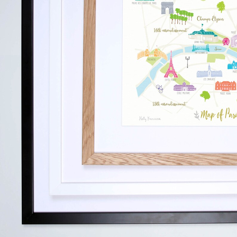 May include: A framed map of Paris, France, with a colorful illustrated design. The map highlights the 15th and 16th arrondissements, the Seine River, and the Eiffel Tower. The map is framed in a natural wood frame with a white mat and a black outer frame.