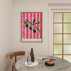 Puede incluir: Una impresi&oacute;n enmarcada de una pintura de una rama de olivo con hojas verdes y aceitunas sobre un fondo a rayas rosa y blanco. La impresi&oacute;n se titula "Olive."