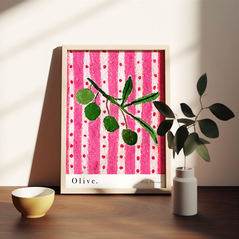 Puede incluir: Una impresi&oacute;n enmarcada de una pintura de acuarela de una rama de olivo con hojas verdes y aceitunas sobre un fondo a rayas rosa y blanco. La impresi&oacute;n tiene la palabra "Olive." en la parte inferior y el nombre del artista en la parte inferior derecha.